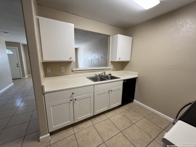 kitchen with white cabinets, light tile patterned floors, black dishwasher, and sink