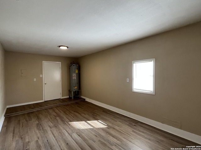 empty room with hardwood / wood-style floors and water heater