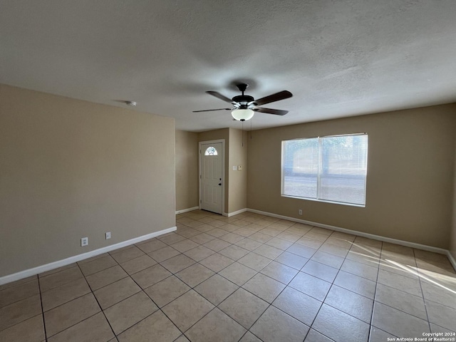 tiled spare room featuring a textured ceiling and ceiling fan