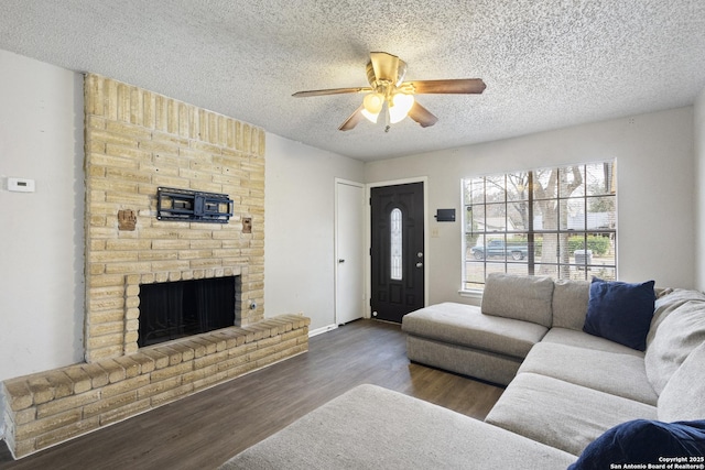 living room featuring ceiling fan, dark hardwood / wood-style flooring, a fireplace, and a textured ceiling