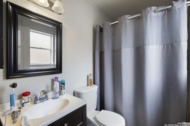 bathroom with toilet, vanity, and a textured ceiling