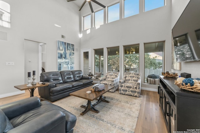 living room featuring ceiling fan, wood-type flooring, and a high ceiling