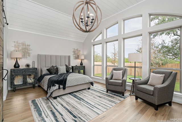 bedroom with wooden ceiling, light hardwood / wood-style floors, vaulted ceiling, and a notable chandelier