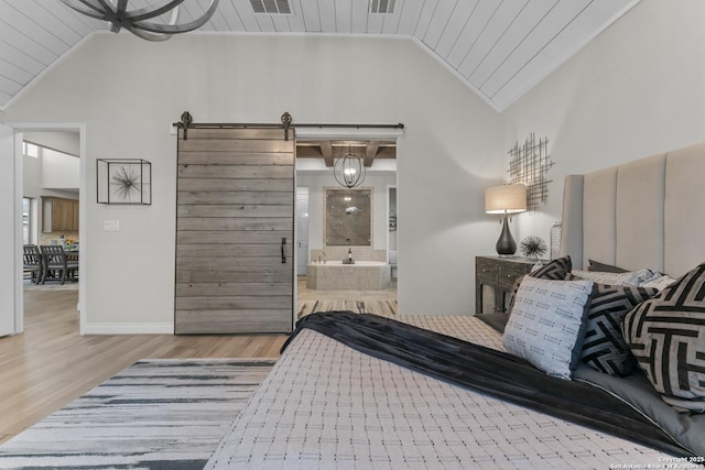 bedroom featuring wooden ceiling, ensuite bathroom, vaulted ceiling, a barn door, and light wood-type flooring