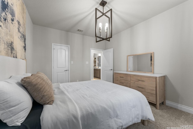 carpeted bedroom with a chandelier and ensuite bath