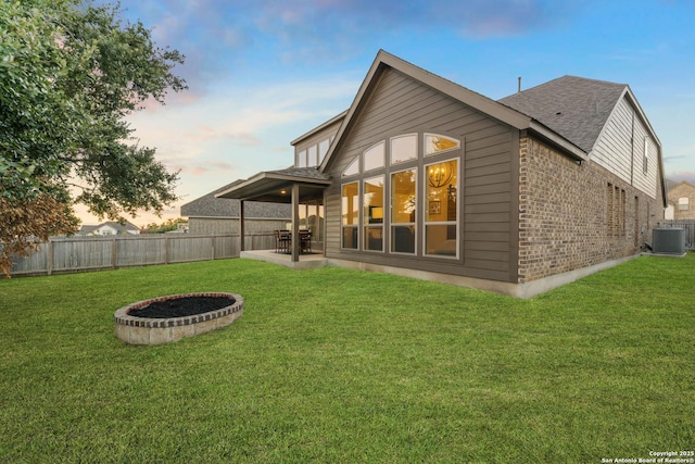 back house at dusk with a yard, a patio, and central AC