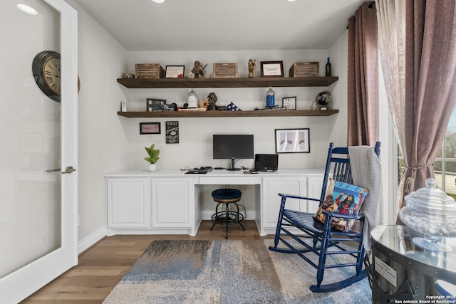 home office with dark wood-type flooring and built in desk