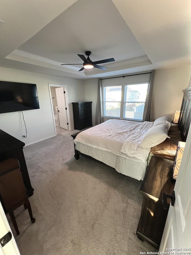 bedroom featuring ceiling fan, dark carpet, a raised ceiling, and ensuite bathroom