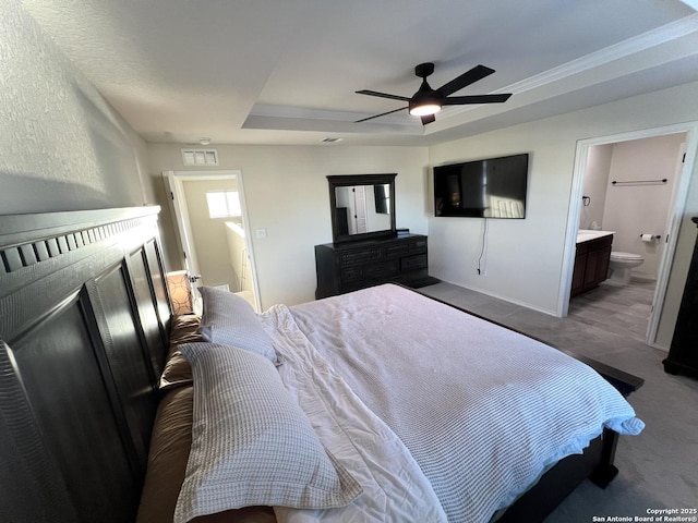 bedroom with ceiling fan, connected bathroom, and a tray ceiling