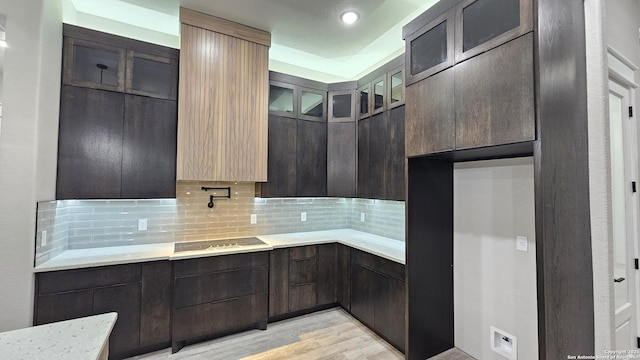 kitchen with light wood-type flooring, decorative backsplash, and dark brown cabinetry