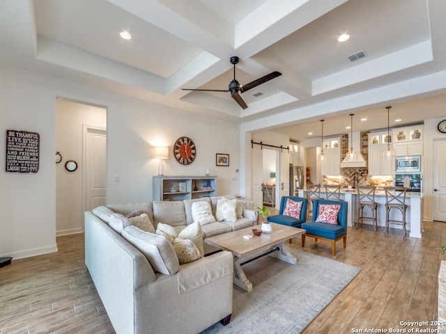 living room with beamed ceiling, a barn door, ceiling fan, and coffered ceiling