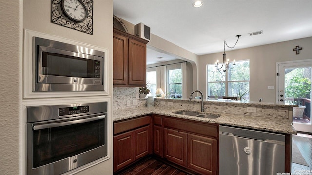 kitchen with kitchen peninsula, stainless steel appliances, a notable chandelier, and sink