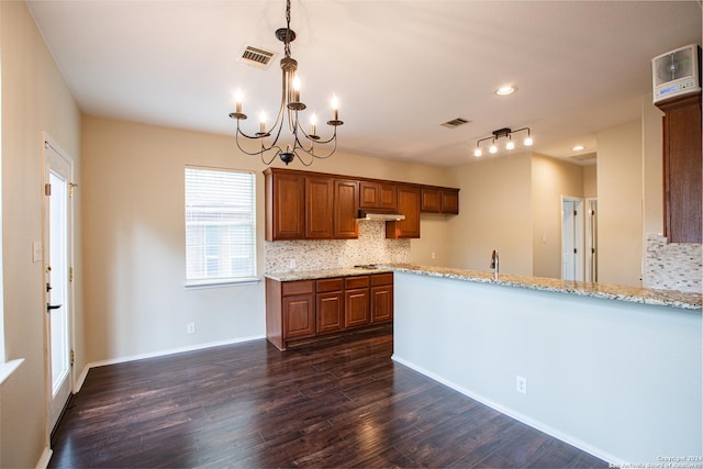 kitchen featuring light stone countertops, dark hardwood / wood-style floors, tasteful backsplash, and a notable chandelier