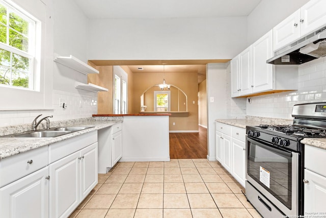 kitchen featuring light tile patterned floors, stainless steel gas range, kitchen peninsula, pendant lighting, and white cabinets