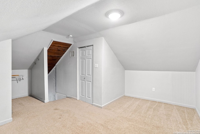 bonus room featuring a textured ceiling, light colored carpet, and lofted ceiling