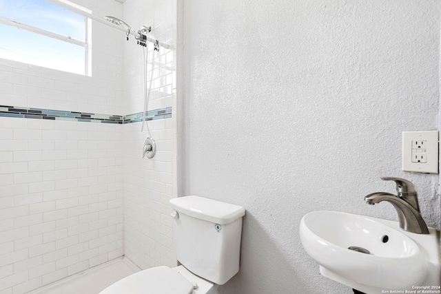 bathroom featuring toilet, sink, and tiled shower