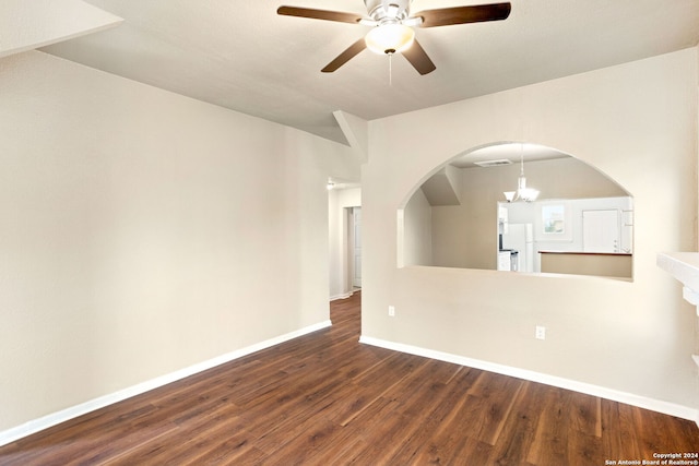 empty room featuring ceiling fan with notable chandelier and dark hardwood / wood-style floors