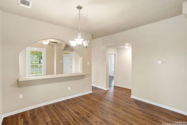 spare room with ceiling fan with notable chandelier and dark hardwood / wood-style floors