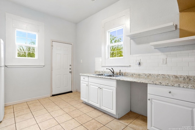 kitchen with tasteful backsplash, white cabinetry, sink, and light tile patterned floors