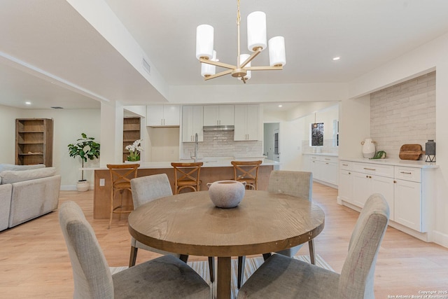 dining room with light hardwood / wood-style floors, sink, and a chandelier