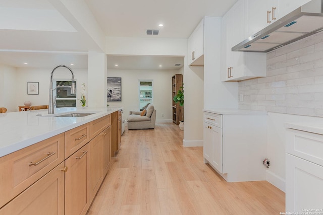 kitchen with decorative backsplash, light wood-type flooring, sink, light brown cabinets, and white cabinets