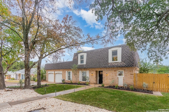 front facade featuring a front yard, fence, a shingled roof, a garage, and brick siding