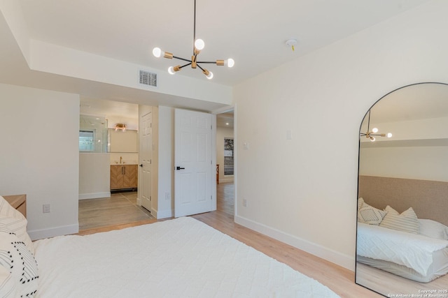 bedroom featuring sink, ensuite bathroom, a notable chandelier, and light hardwood / wood-style floors