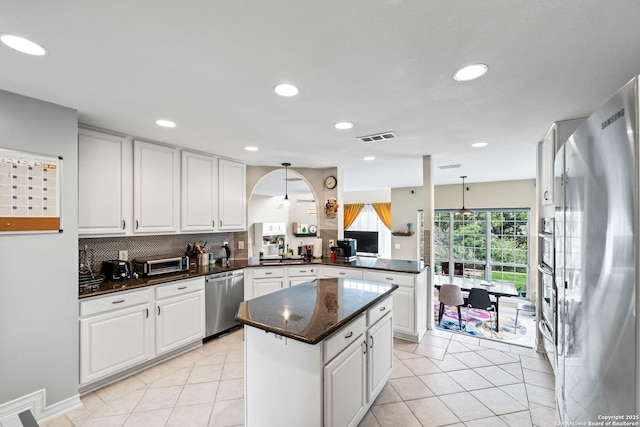 kitchen with white cabinets, hanging light fixtures, decorative backsplash, kitchen peninsula, and stainless steel appliances