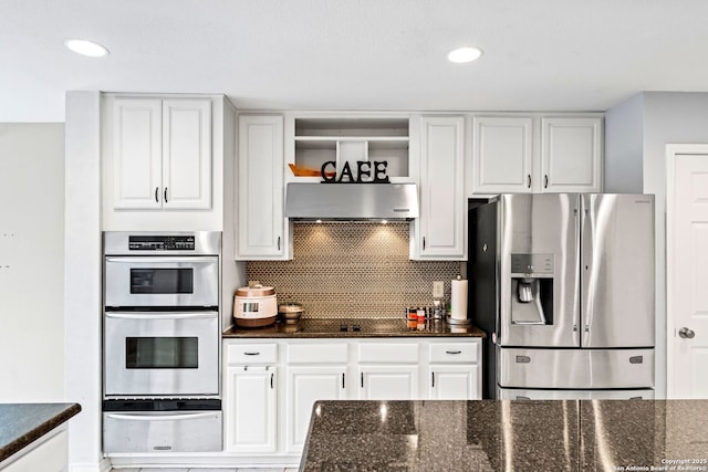 kitchen with white cabinets, backsplash, stainless steel appliances, and dark stone countertops