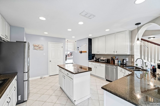 kitchen featuring stainless steel appliances, sink, pendant lighting, a center island, and white cabinetry