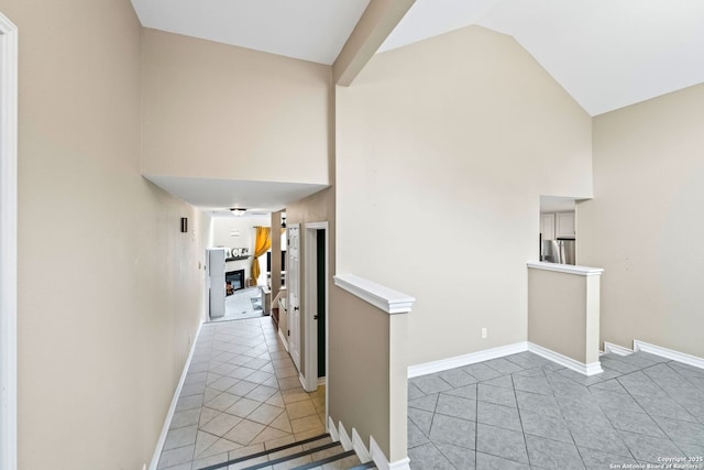 hallway featuring high vaulted ceiling and light tile patterned flooring