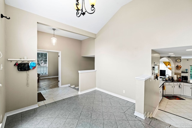 tiled entrance foyer with an inviting chandelier, sink, and vaulted ceiling