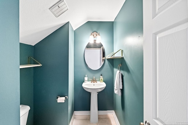 bathroom with tile patterned flooring, vaulted ceiling, and toilet