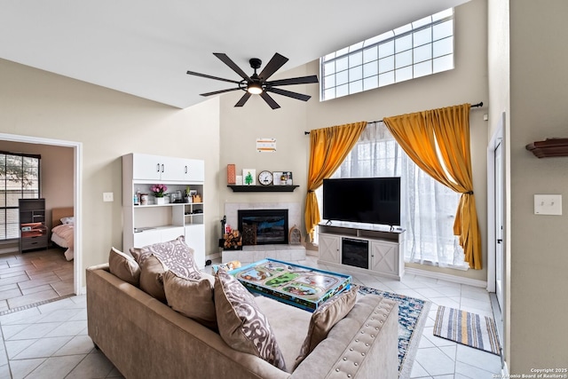 tiled living room featuring ceiling fan and a tiled fireplace