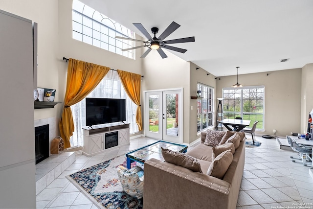 tiled living room with a fireplace, a wealth of natural light, and ceiling fan