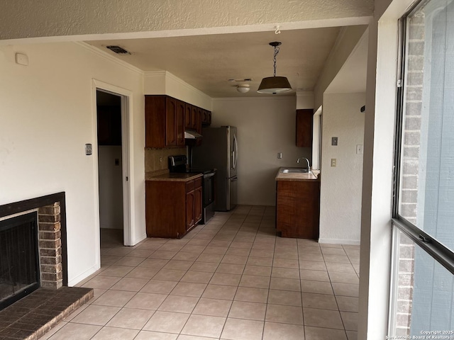 kitchen with dark brown cabinetry, sink, a brick fireplace, electric stove, and light tile patterned flooring