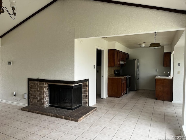 kitchen featuring an inviting chandelier, sink, a brick fireplace, light tile patterned floors, and electric range oven