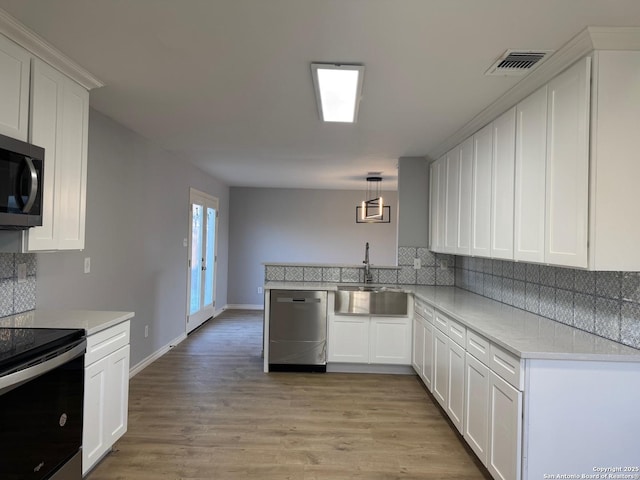 kitchen featuring appliances with stainless steel finishes, white cabinetry, pendant lighting, and sink