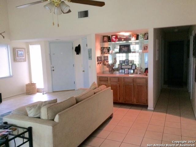 living room featuring a high ceiling, ceiling fan, and light tile patterned flooring