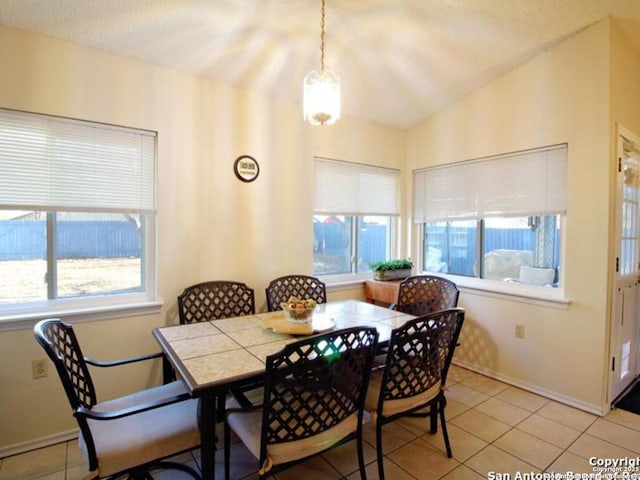 dining area with lofted ceiling, light tile patterned floors, and a textured ceiling