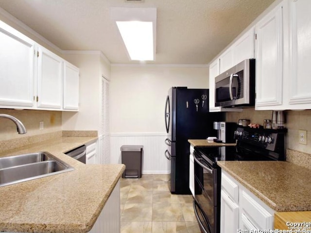 kitchen with kitchen peninsula, appliances with stainless steel finishes, crown molding, sink, and white cabinetry