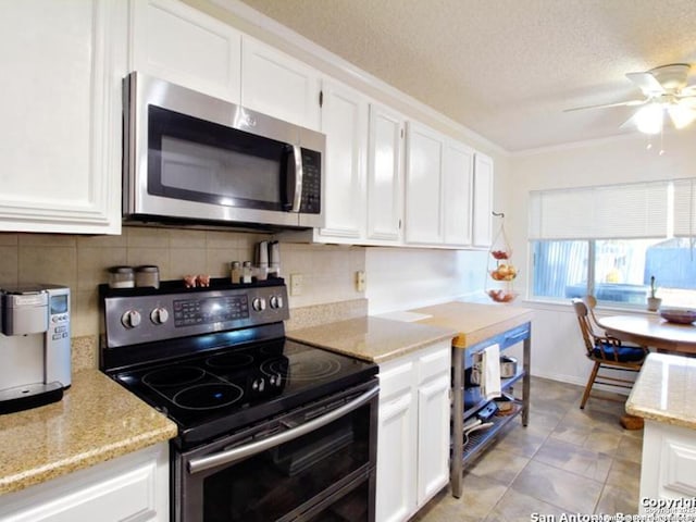 kitchen featuring white cabinets, a textured ceiling, stainless steel appliances, and light stone counters