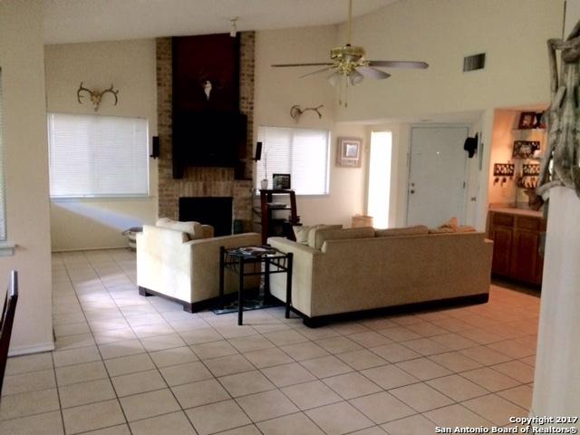 living room with light tile patterned floors, vaulted ceiling, a brick fireplace, and ceiling fan