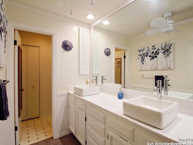 bathroom with a textured ceiling, vanity, ceiling fan, and ornamental molding