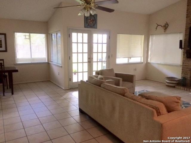 living room with ceiling fan, french doors, light tile patterned flooring, and lofted ceiling