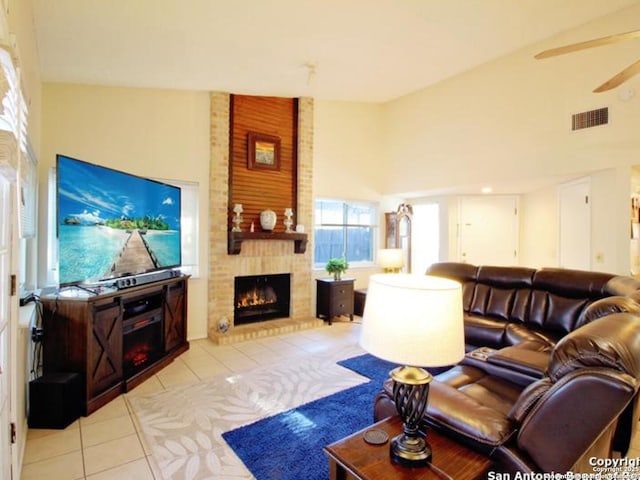 living room featuring ceiling fan, light tile patterned floors, a fireplace, and high vaulted ceiling