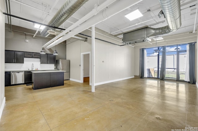 interior space featuring a towering ceiling, appliances with stainless steel finishes, a center island, and sink