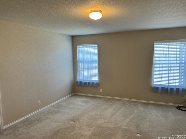 spare room featuring light carpet and a textured ceiling