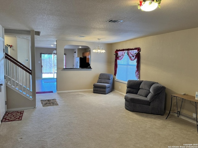 unfurnished living room featuring carpet, a textured ceiling, and an inviting chandelier