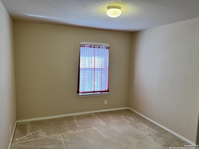 empty room with light colored carpet and a textured ceiling